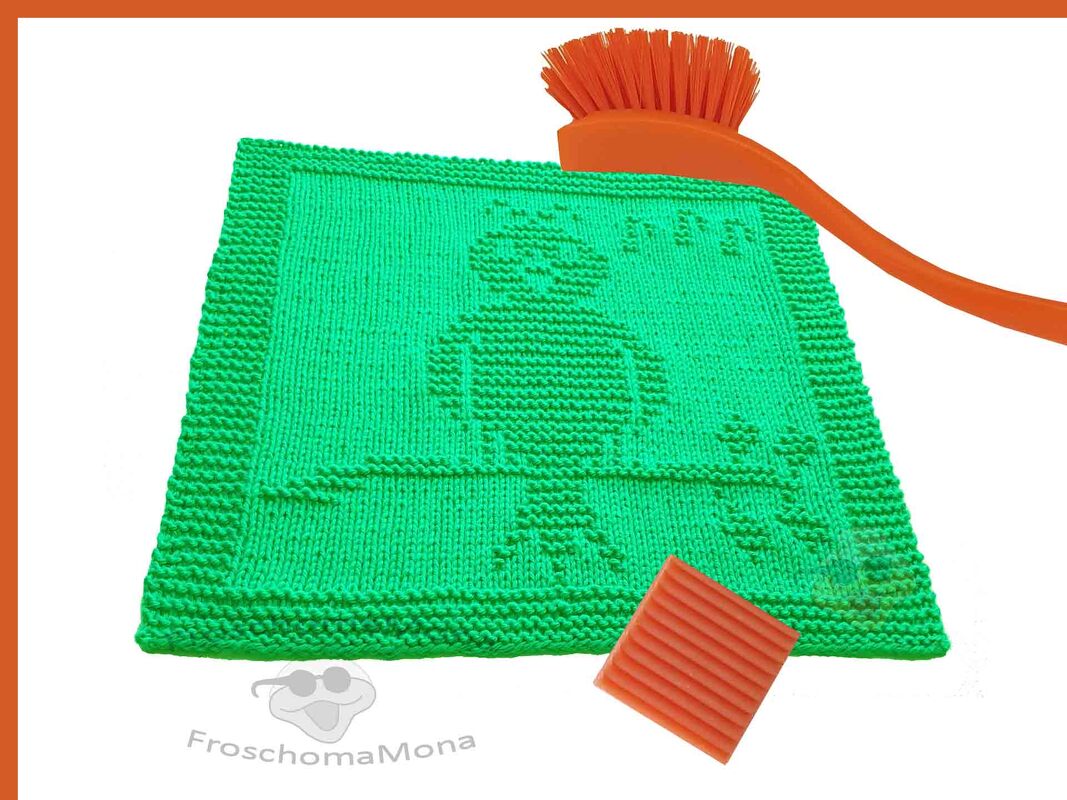 Quadratisches grünes gestricktes Spültuch mit Vogelmotiv, daneben orange Bürste und Seifenstück