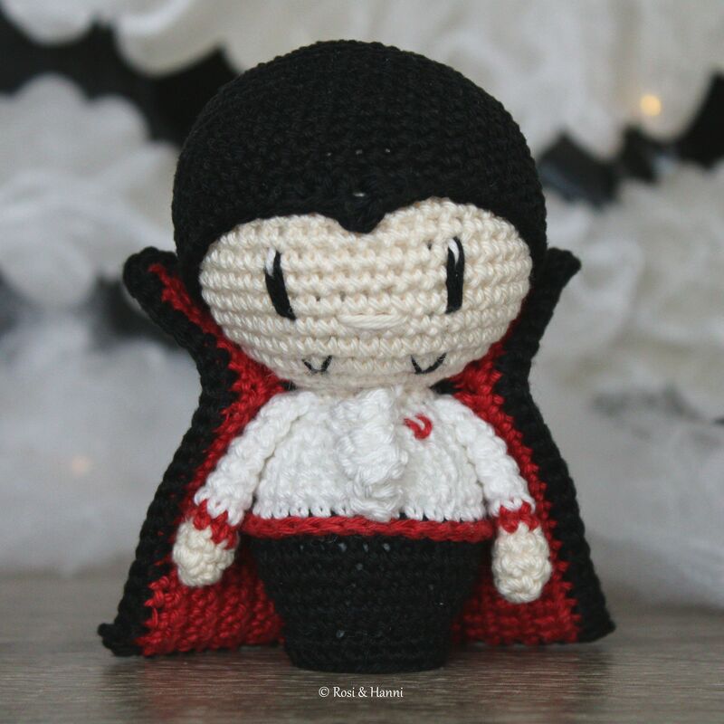 Gehäkelter Vampir‑Amigurumi mit schwarzem Umhang und rotem Futter