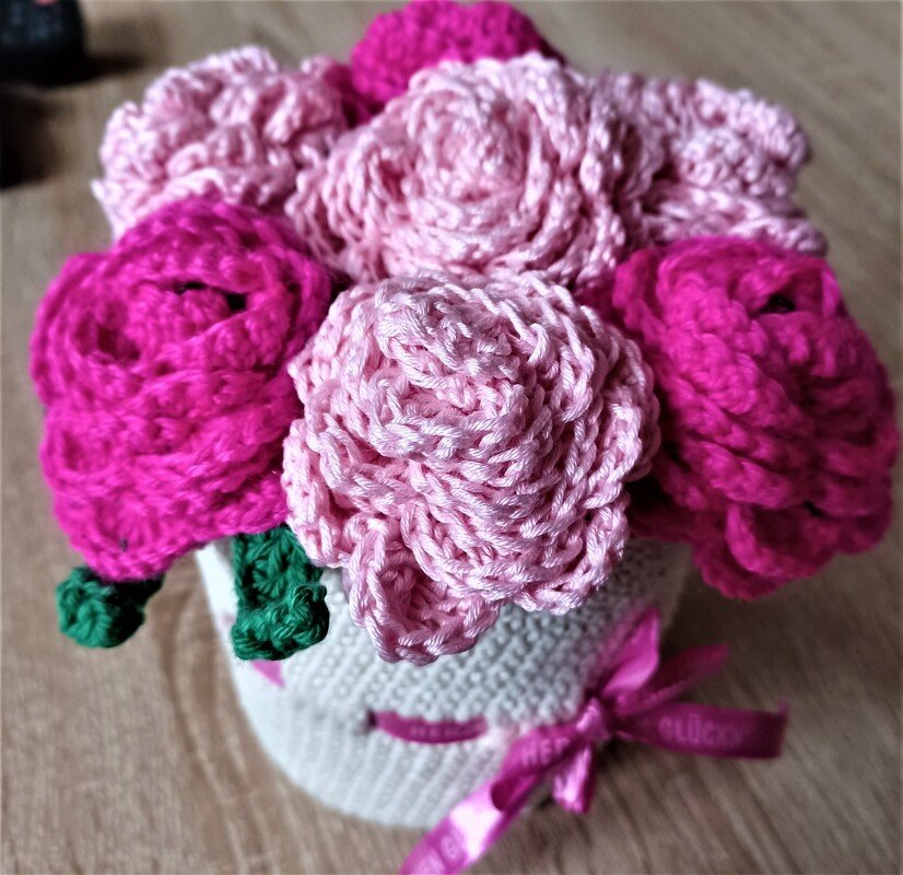 Kompakter Häkelstrauß mit rosa und pinken Rosen in weißem Topf