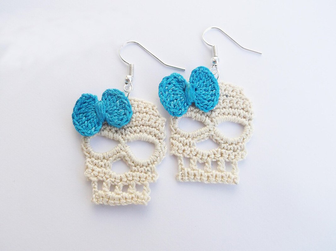 Cream crocheted skull dangle earrings with turquoise bows and silver hooks