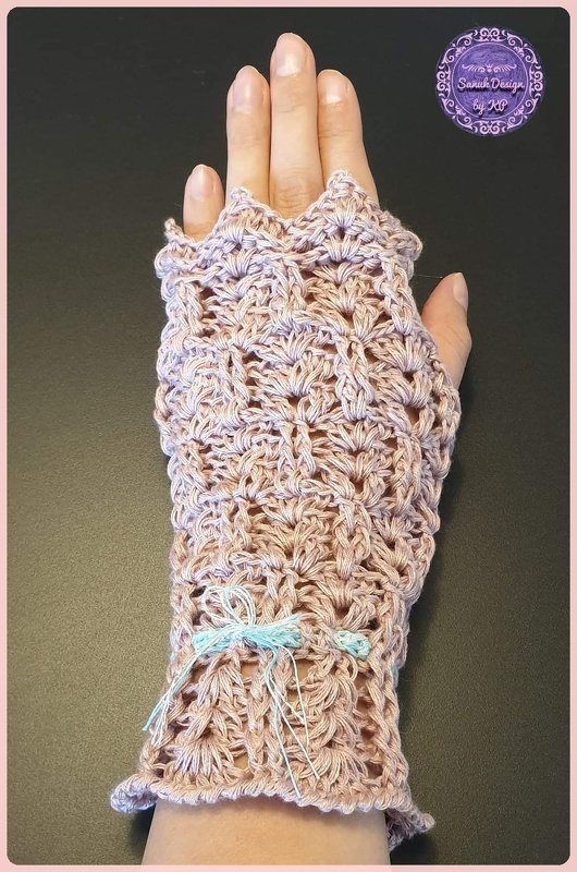 Hand mit gehäkelter, fingerloser Damenstulpe in hellem Rosa mit blauem Zierband