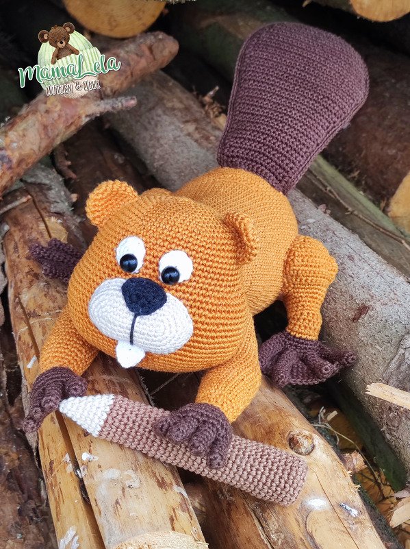 Gehäkelter Amigurumi-Biber in Orangebraun mit Ast auf geschichteten Holzscheiten
