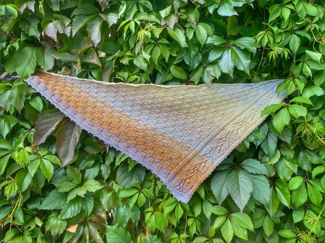 Triangle crochet shawl laid flat showing gradient colors and textured lattice stitch