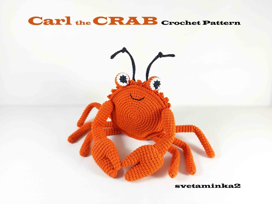 Bright orange crocheted amigurumi crab with spiral body, separate claws, and eye stalks on white background