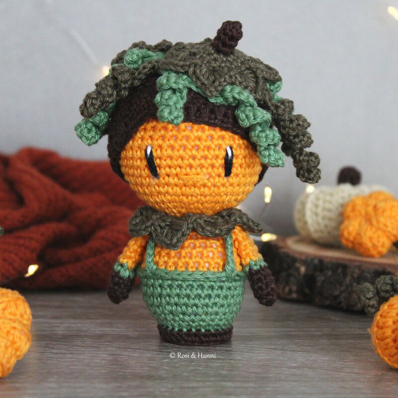 Gehäkelter Kürbis-Amigurumi mit grüner Latzhose und Blätterhut