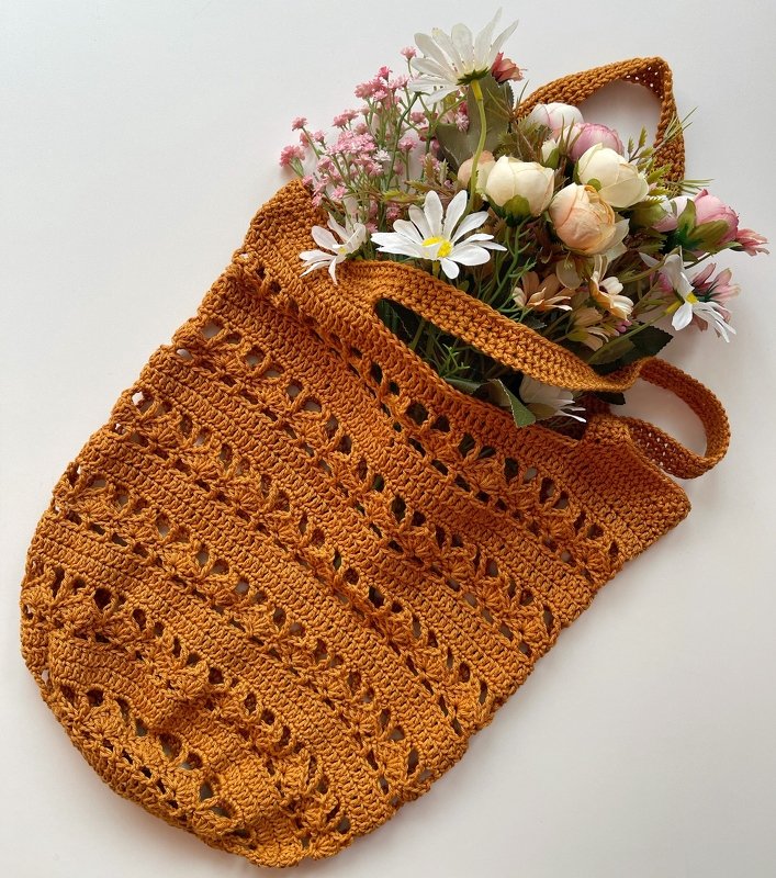 Rust-orange crocheted shopper bag with openwork pattern and flowers inside