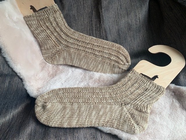 Beige gestrickte Herrensocken auf Holzspannern mit Rippenmuster