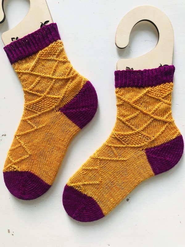 Gestrickte senfgelbe und violette Socken mit Rautenmuster auf Sockenformen
