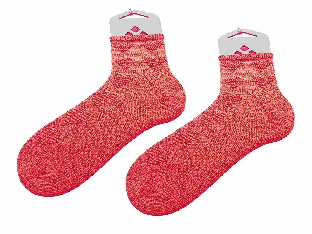 Korallenrote gestrickte Socken mit Herzmuster auf weißen Haltern