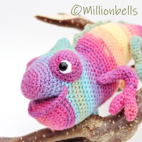 Vibrant crocheted rainbow chameleon amigurumi perched on a branch