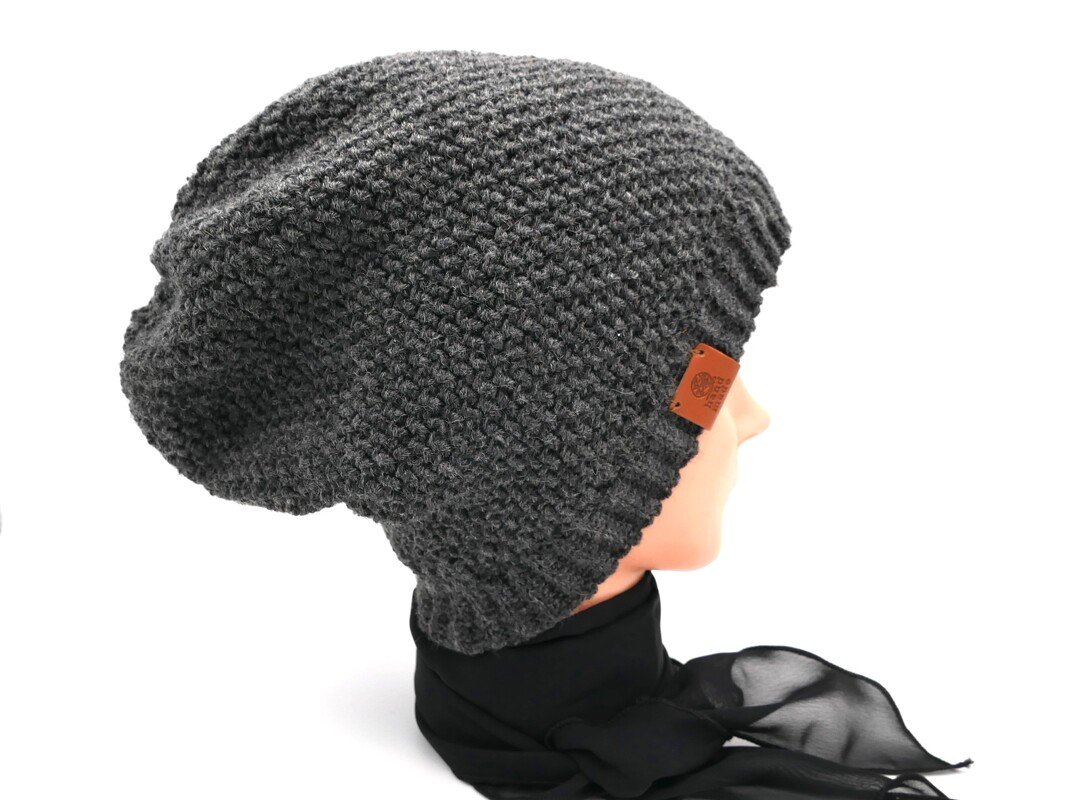 Dunkelgraue gehäkelte Slouch-Beanie auf Schaufensterkopf mit schwarzem Tuch