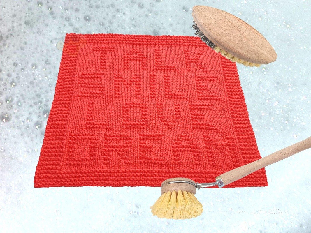Rotes gestricktes Spültuch mit erhabenem Schriftzug 'TALK SMILE LOVE DREAM' in Seifenschaum mit Bürsten