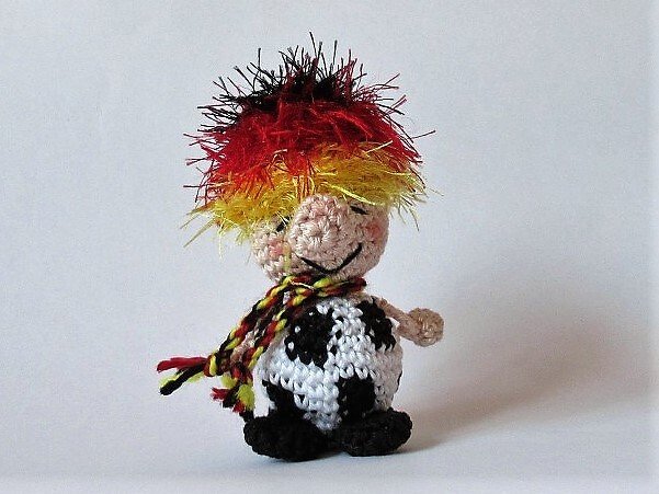 Häkel-Amigurumi mit Fußball, buntem Haar und Schal
