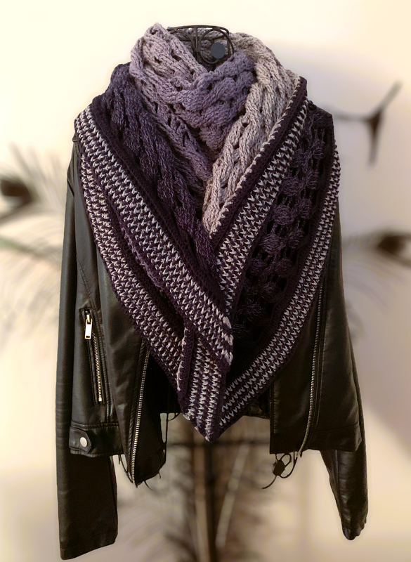 Triangle crochet shawl in dark purple and lavender gradient with textured and lacy panels, draped over a black jacket on a dress form