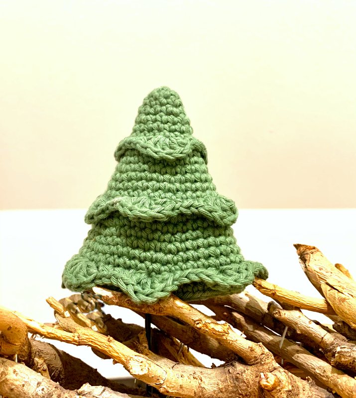 Kleiner gehäkelter Weihnachtsbaum auf Holzunterlage