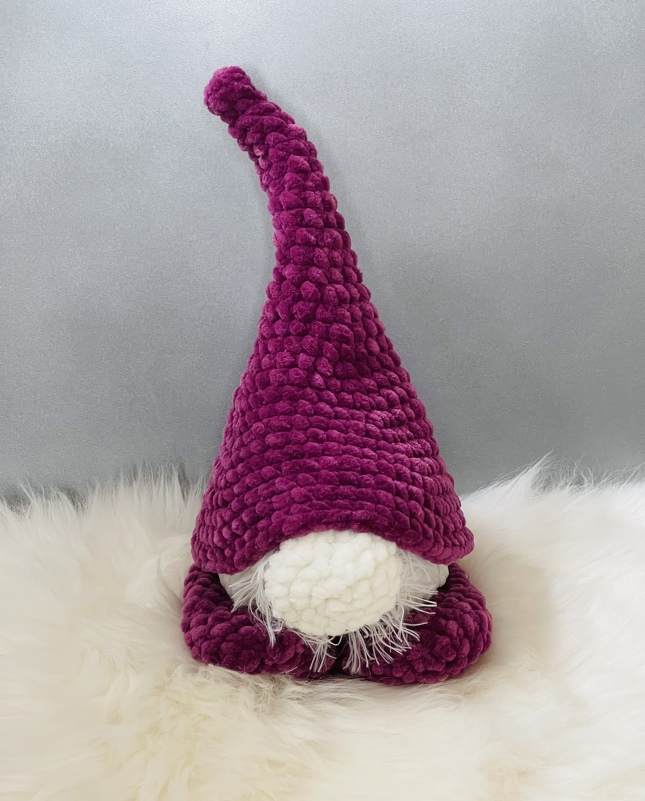 Gehäkelter Wichtel in Beerenton mit hoher spitzer Mütze, weißer runder Nase und flauschigem Bart