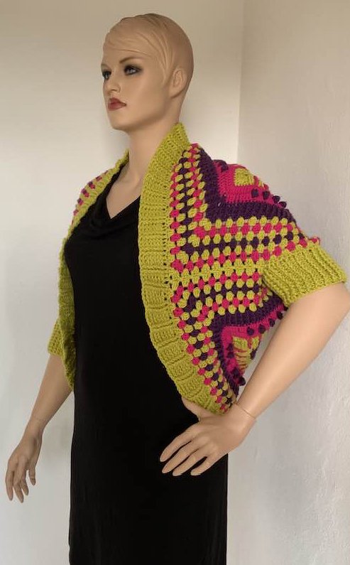 Gehäkelter Seelenwärmer in Limonengrün, Pink und Violett auf Mannequin, offene Front und kurze Ärmel