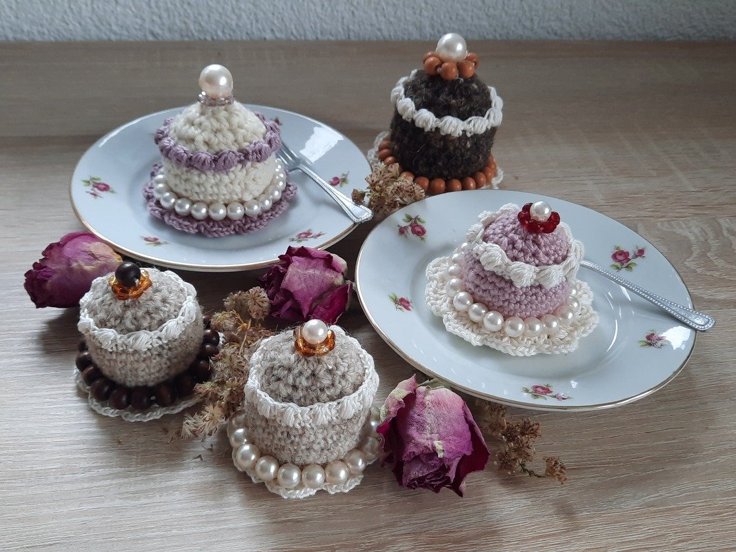 Vintage-Häkel-Törtchen in Pastell und Naturtönen mit Perlen umgeben von getrockneten Rosen