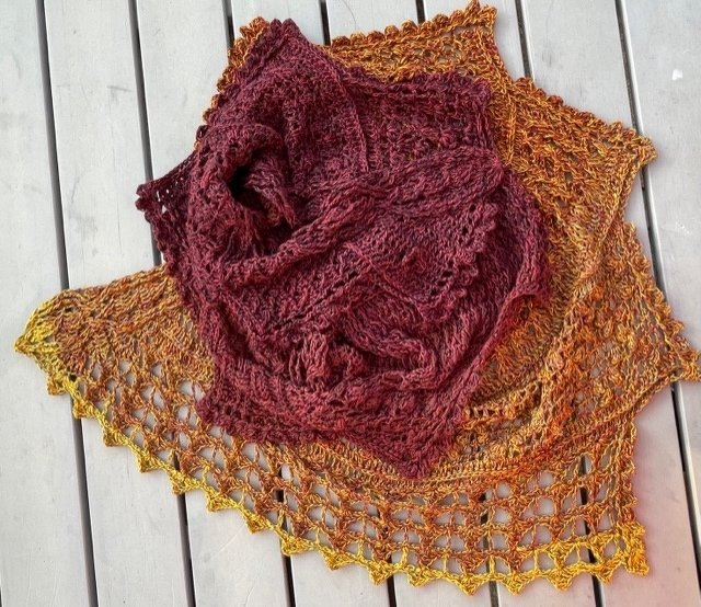 Zwei gehäkelte Dreieckstücher in Burgunderrot und Gelborange mit Lochmuster auf hellem Holz.