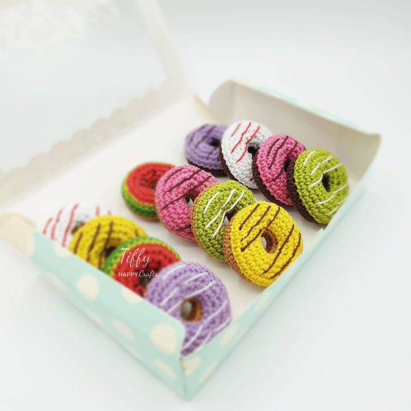 assortment of colorful crochet mini donuts with stitched drizzle in a polka-dot box