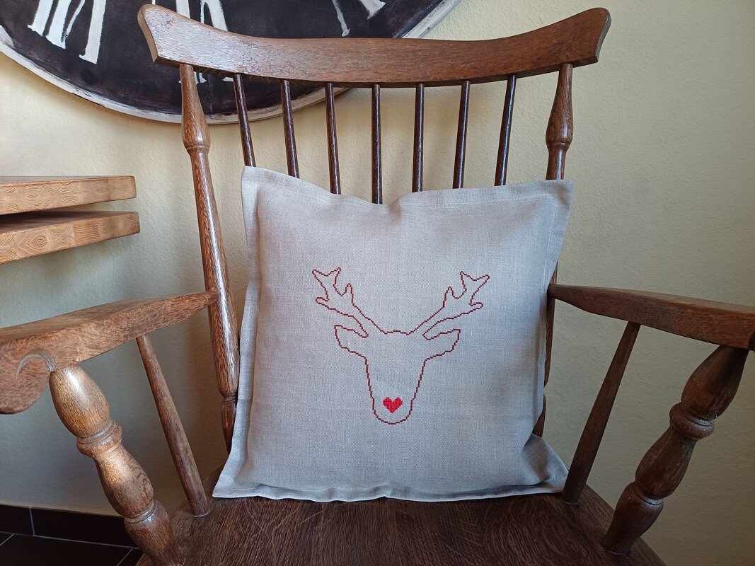 Kissen mit umrissbasiertem Kreuzstich-Rentier und rotem Herz auf einem Holzstuhl