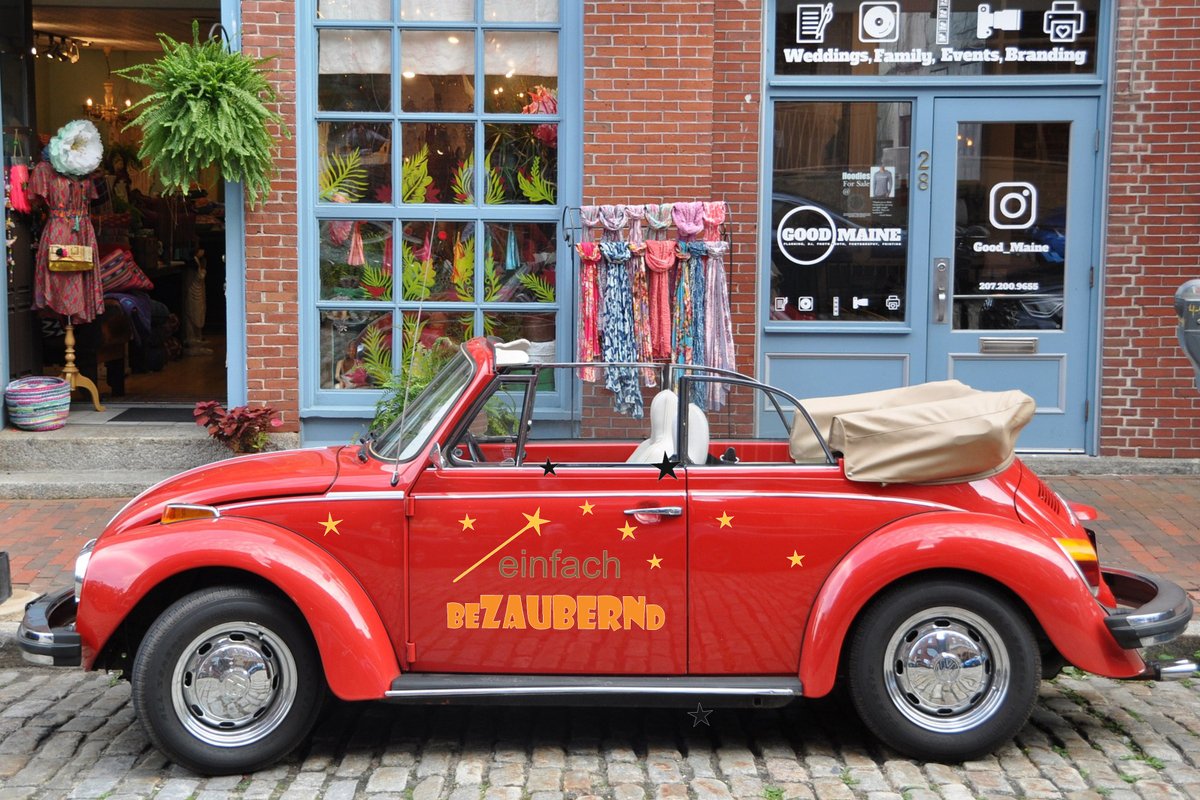 Rotes Cabriolet mit Sternen und Schriftzug „einfach bezaubernd“ auf Kopfsteinpflaster