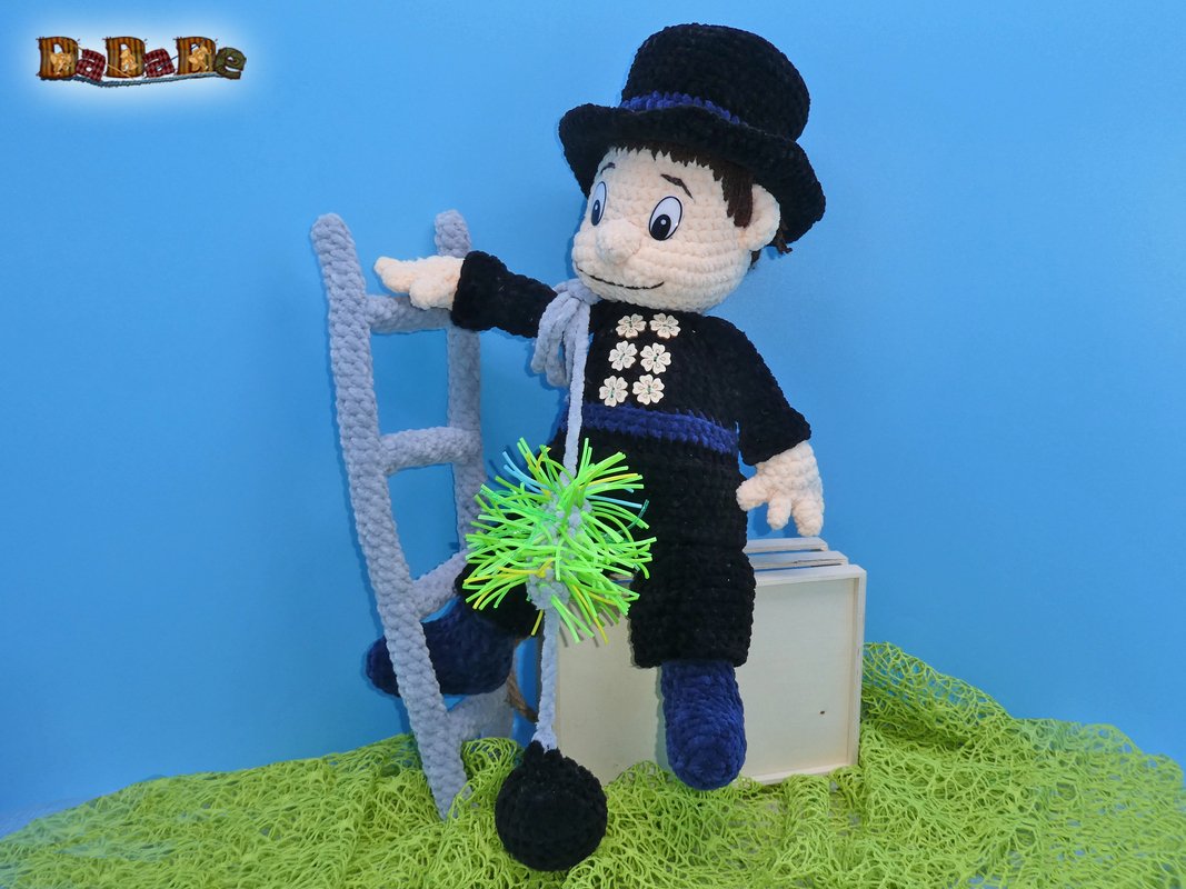 Gehäkelte Amigurumi-Figur eines Schornsteinfegers mit Zylinder, Leiter und Bürste