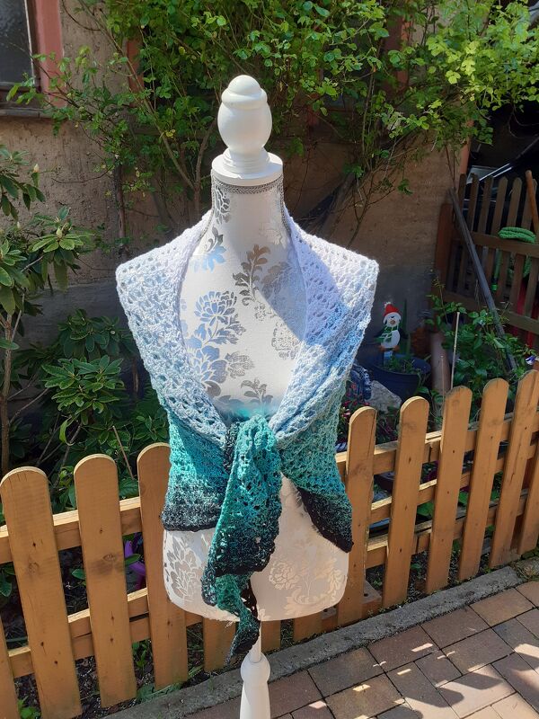 Gehäkeltes Dreieckstuch mit Farbverlauf von Hellblau über Türkis zu Dunkelblau und Schwarz auf Schneiderpuppe im Garten