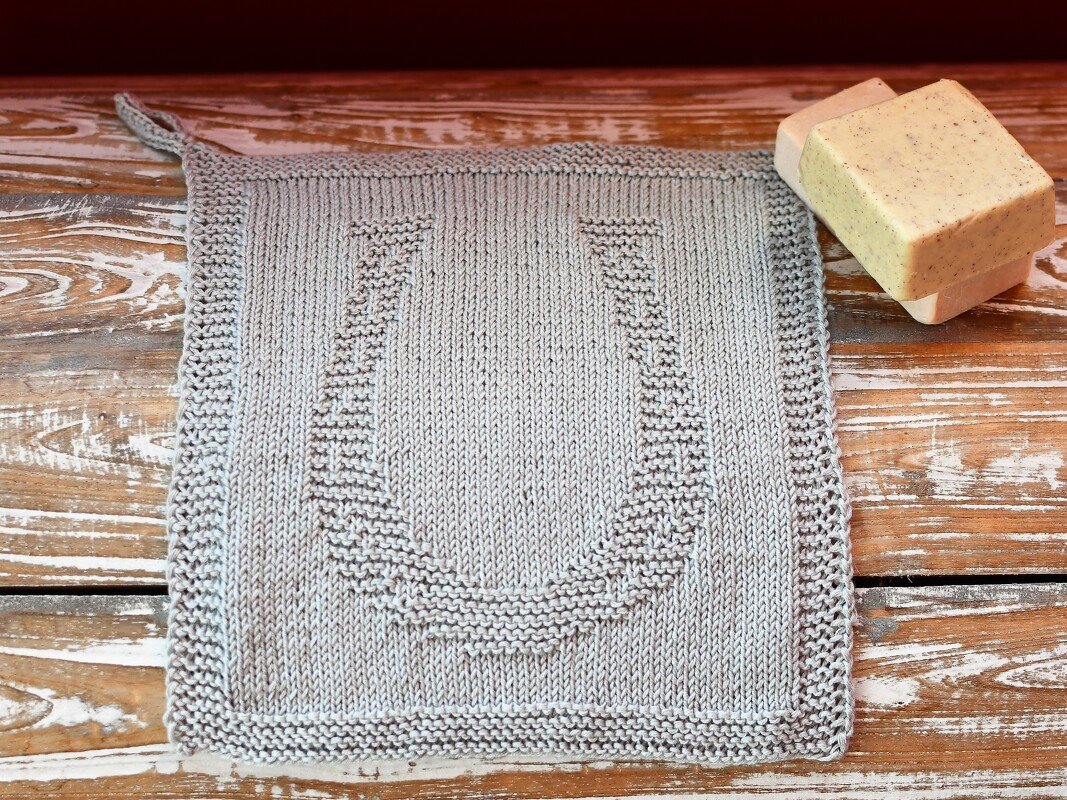 Hellgraues gestricktes Quadrat mit geprägtem Hufeisen-Relief, krauser Rand und Aufhängeschlaufe