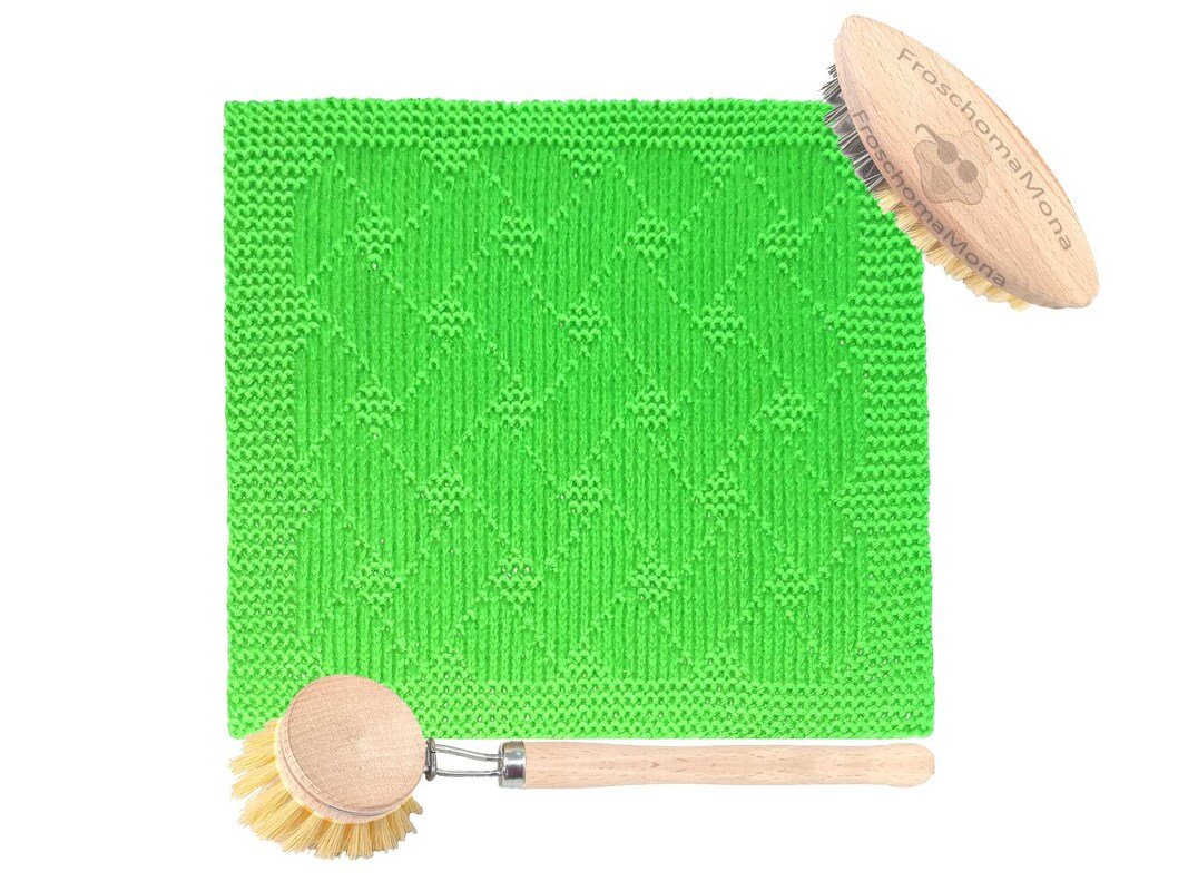 Grünes gestricktes Tuch mit Rautenmuster neben zwei Holzbürsten