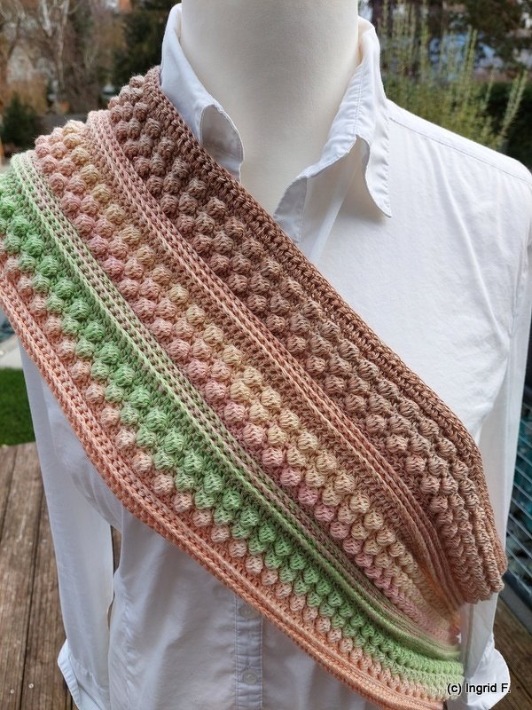 multicolored crocheted bobble cowl draped over a white-shirted mannequin