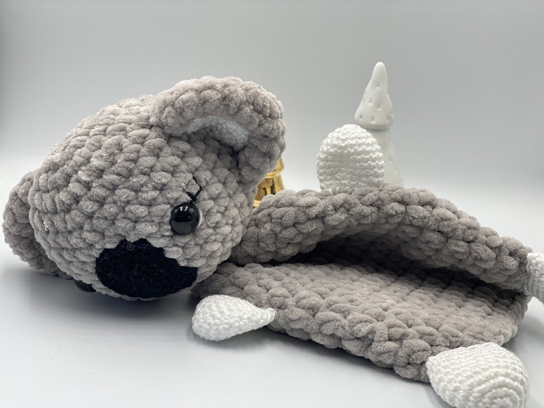 Grey crocheted koala lovey with plush textured blanket and white paws