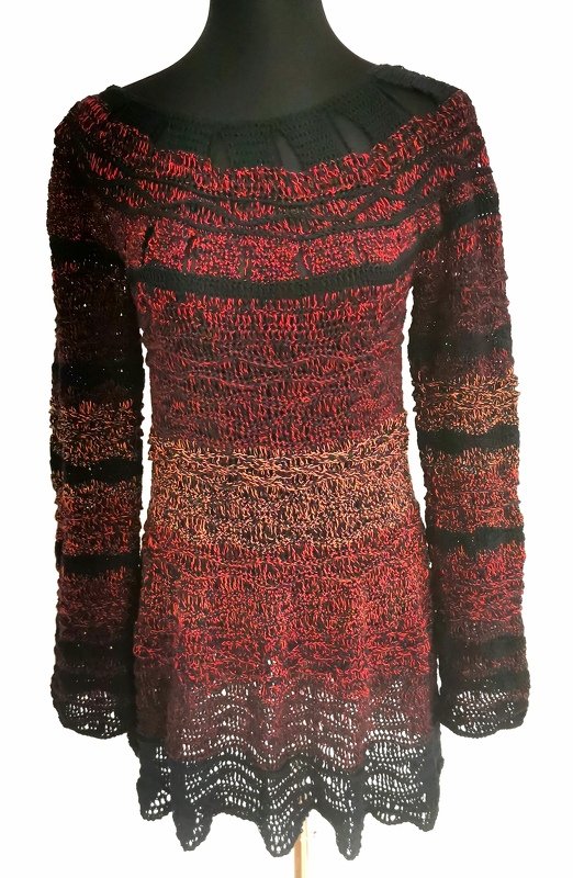 Gehäkelter Damenpullover in Rot und Schwarz mit langen Ärmeln und Spitzenborte am Saum auf einer Schneiderpuppe.