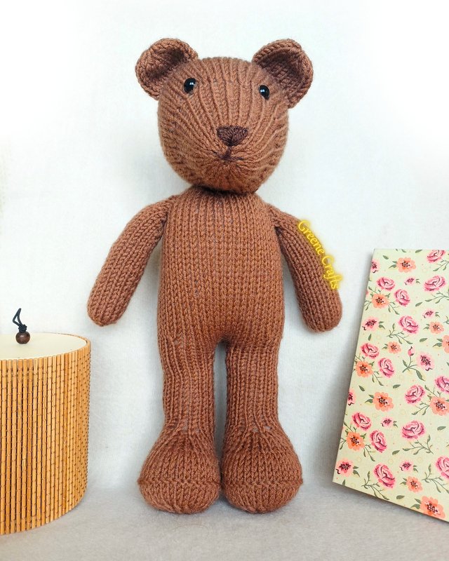Brown hand-knitted teddy bear with long arms and legs, black bead eyes and a stitched nose