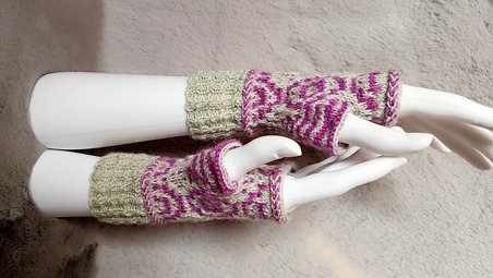 Zwei gestrickte fingerlose Armstulpen in Lila und Beige mit geometrischem Muster auf weißen Mannequinarmen