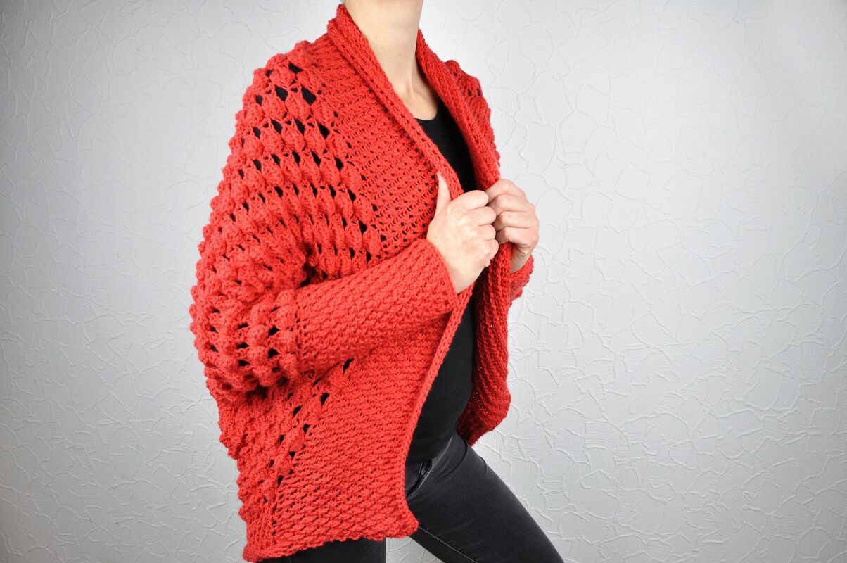 Person trägt roten gehäkelten Seelenwärmer mit Schalkragen über dunklem Top