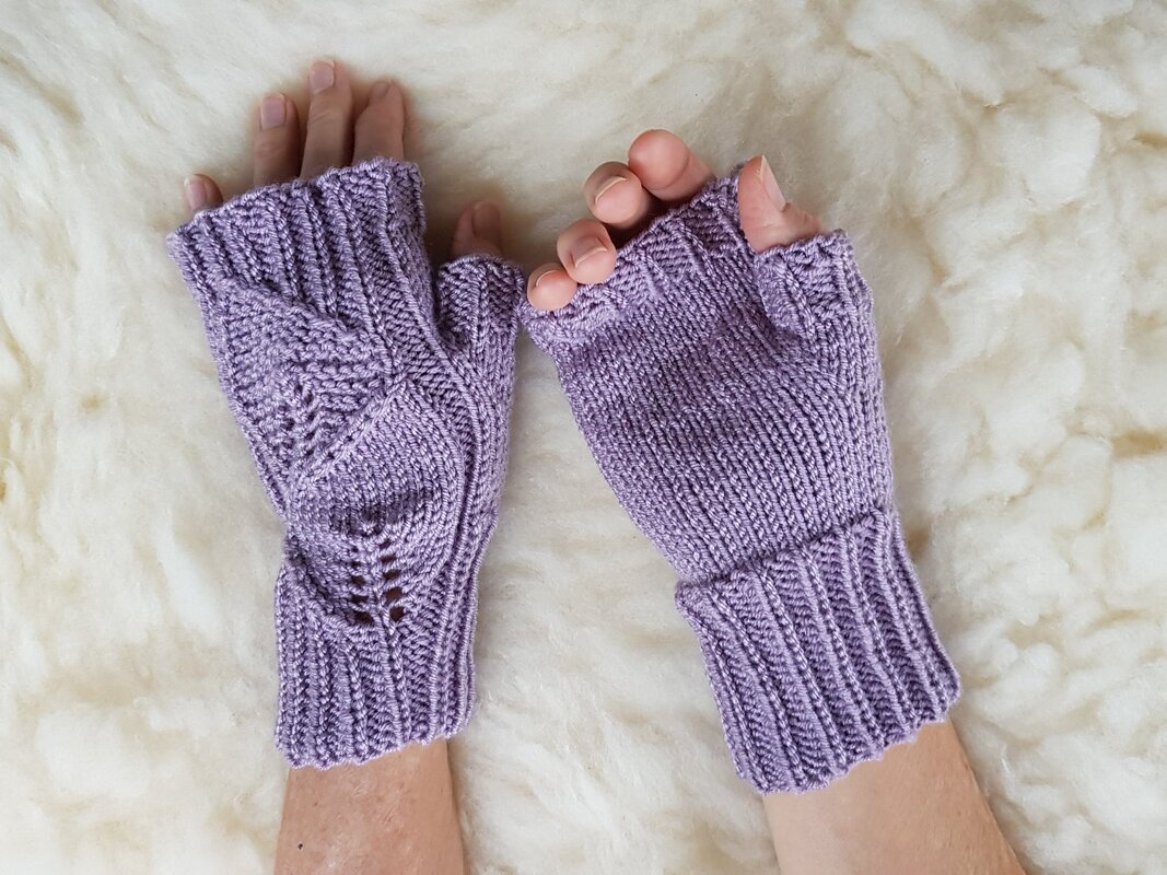 Fingerlose fliederfarbene Handschuhe mit Daumenöffnung und verlängertem Rippbündchen auf hellem Untergrund