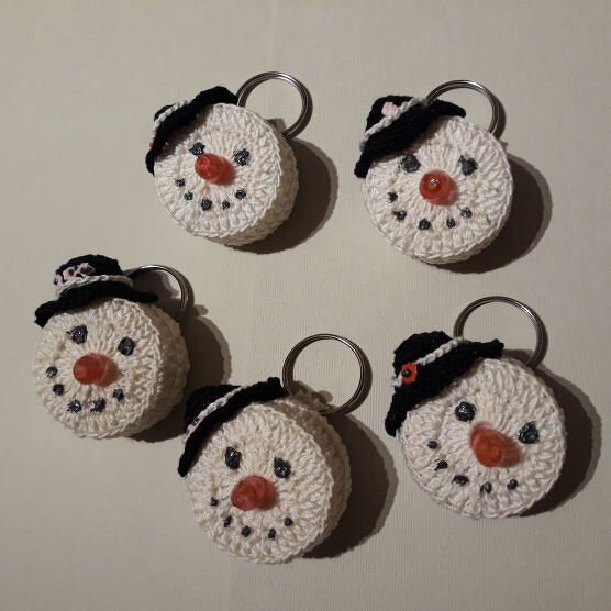 Fünf gehäkelte Schnemann‑Schlüsselanhänger mit schwarzen Hüten und Metallringen