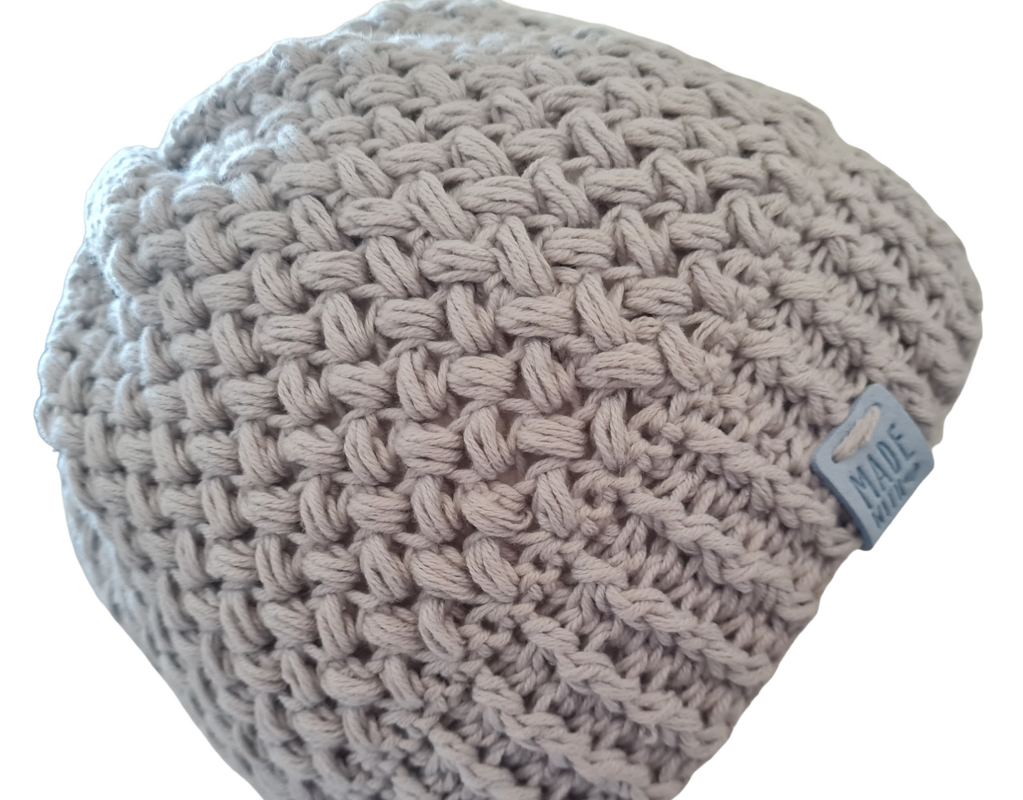 Hellgraue gehäkelte Beanie mit ausgeprägtem Strukturmuster und kleinem Etikett an der Seite.