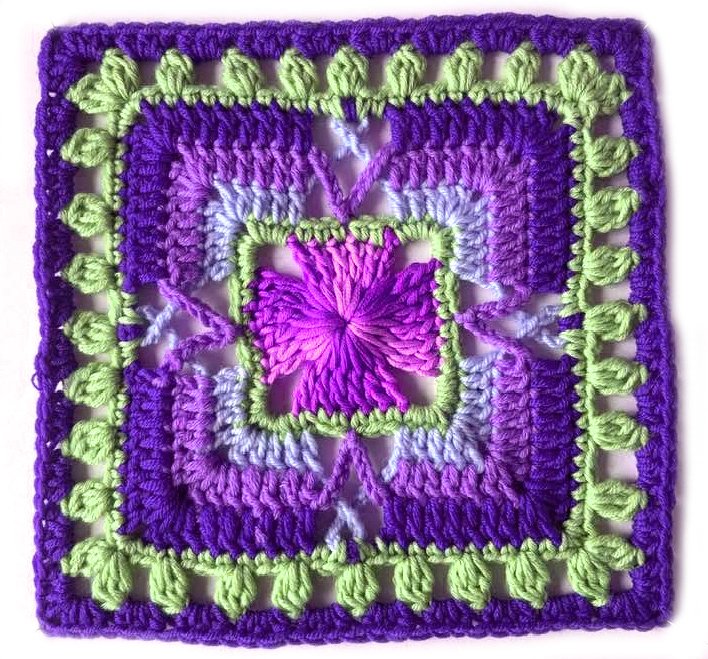 Gehäkeltes Quadrat mit zentralem Blütenstich, abgestuften violetten Runden und grüner Blattborte