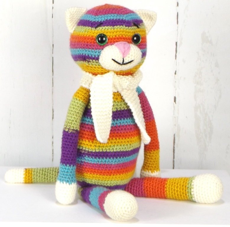 Mehrfarbige, gestreifte Amigurumi-Katze mit langen Beinen und weißem Schal