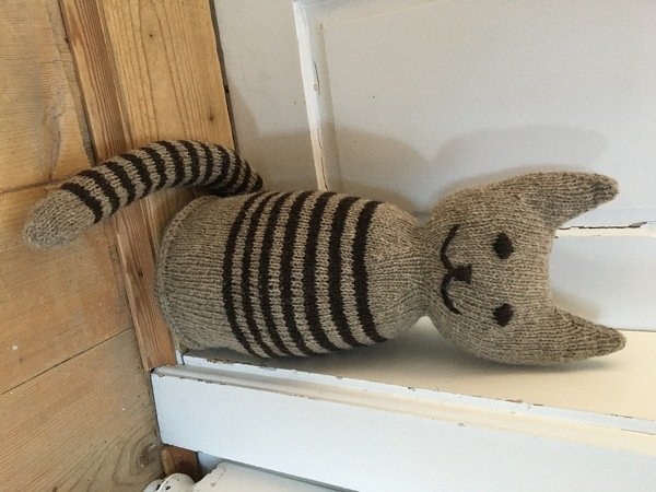 Gestrickte Katzenfigur mit gestreiftem Körper und aufgesticktem Gesicht