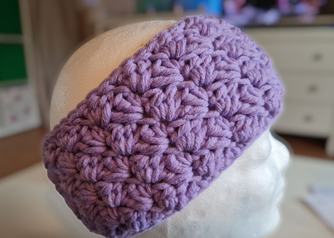 Fliederfarbenes gehäkeltes Stirnband mit Puffstich-Relief auf Schaufensterkopf