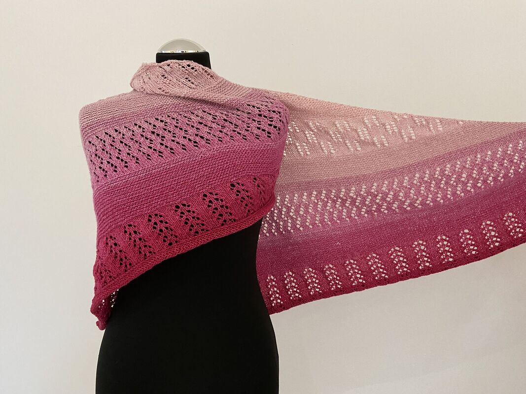 Gestricktes Dreieckstuch in Rosa-Pink Verlauf mit Lochmuster auf schwarzer Schneiderpuppe