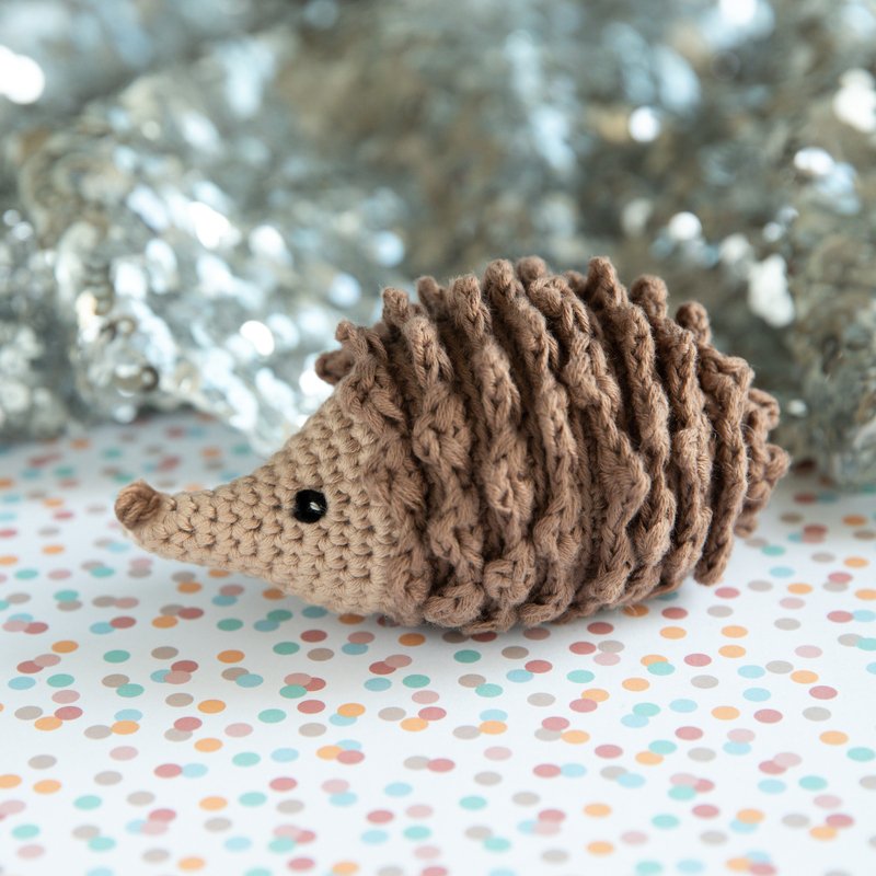 Gehäkelter brauner Igel Amigurumi mit gewellten Stacheln auf gepunktetem Papier