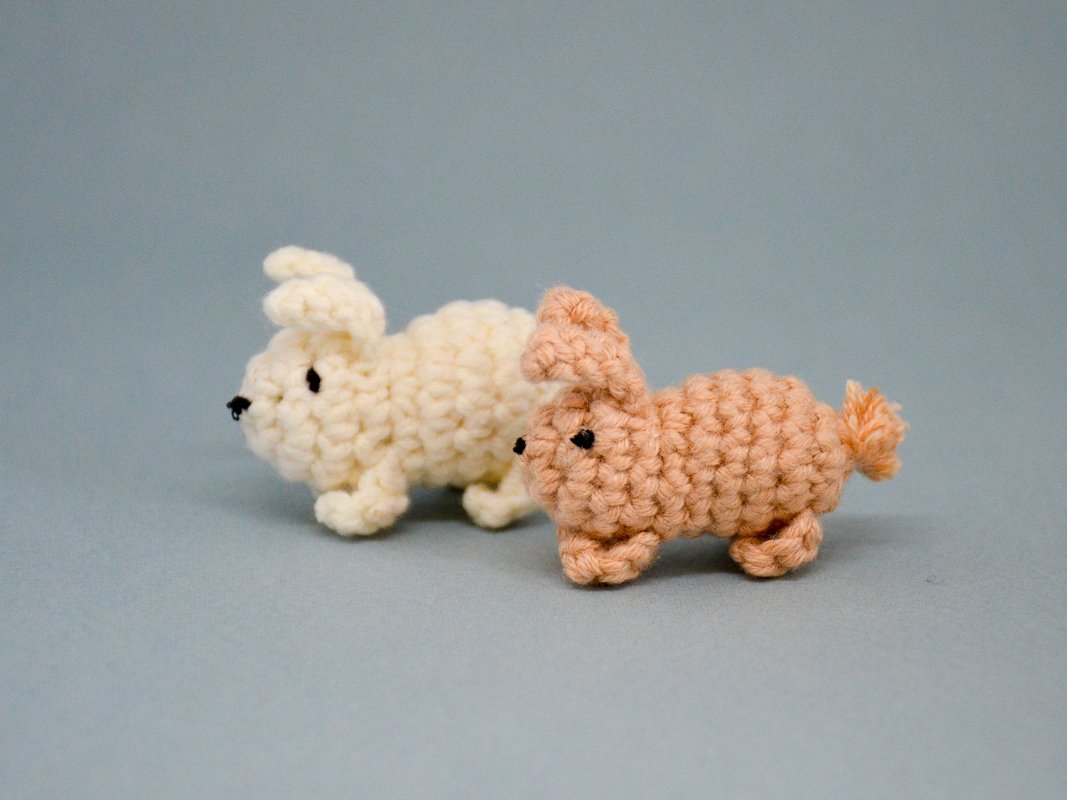 Side view of two small crochet amigurumi rabbits showing stitch texture and proportions