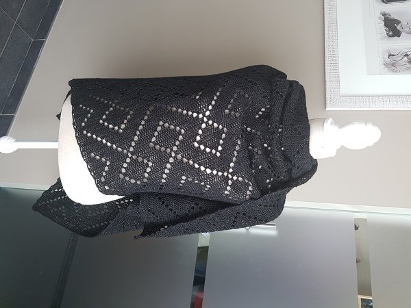 Black crochet shawl on a mannequin displaying a geometric openwork lace pattern.