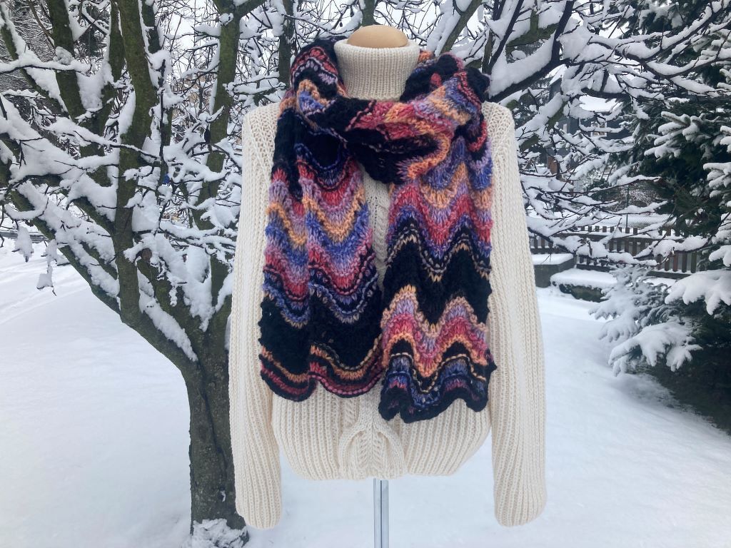 Farbenfroher Schal mit Wellenmuster auf Pullover im Schnee