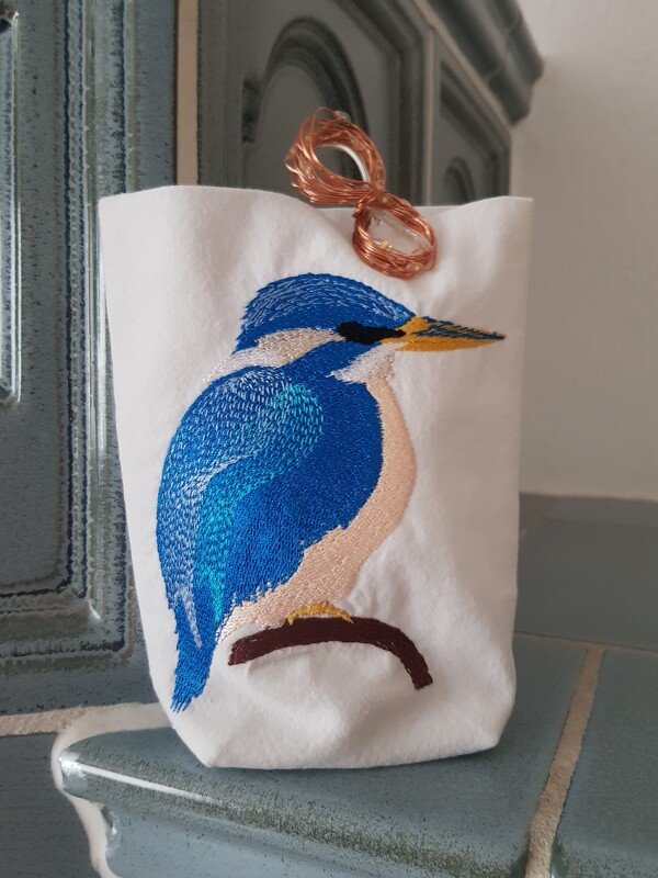 Weißer Stoffbeutel mit gesticktem blauen Eisvogel auf Ast und zarter Lichterkette