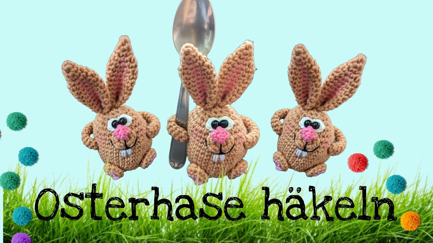 Drei kleine gehäkelte Amigurumi-Osterhasen in karamellbraun mit großen Ohren, rosa Nase und weißen Augen; der mittlere Hase neben einem Löffel. Hellblauer Hintergrund, grüne Grasfläche und bunte Pompons.